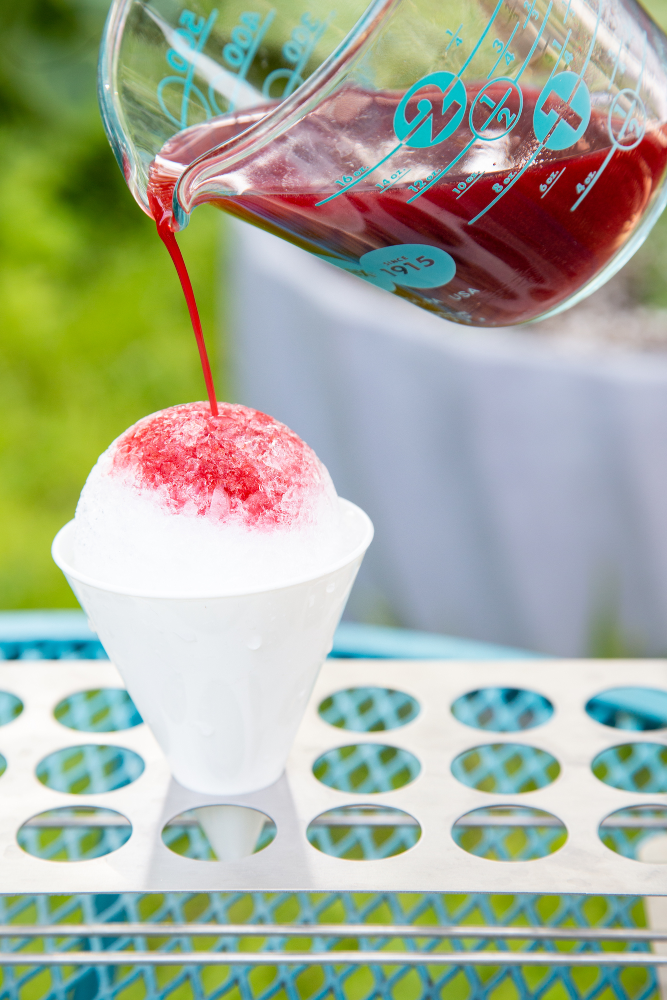pouring cherry syrup on a sno cone