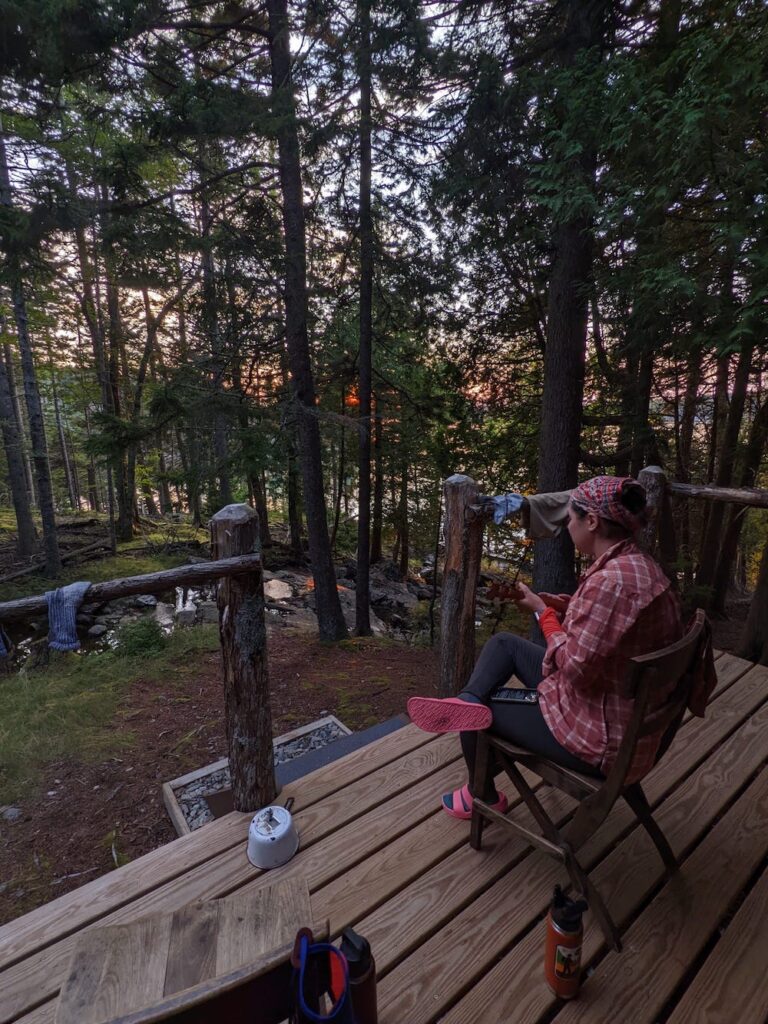 woman playing ukulele on a cabin porch in the woods