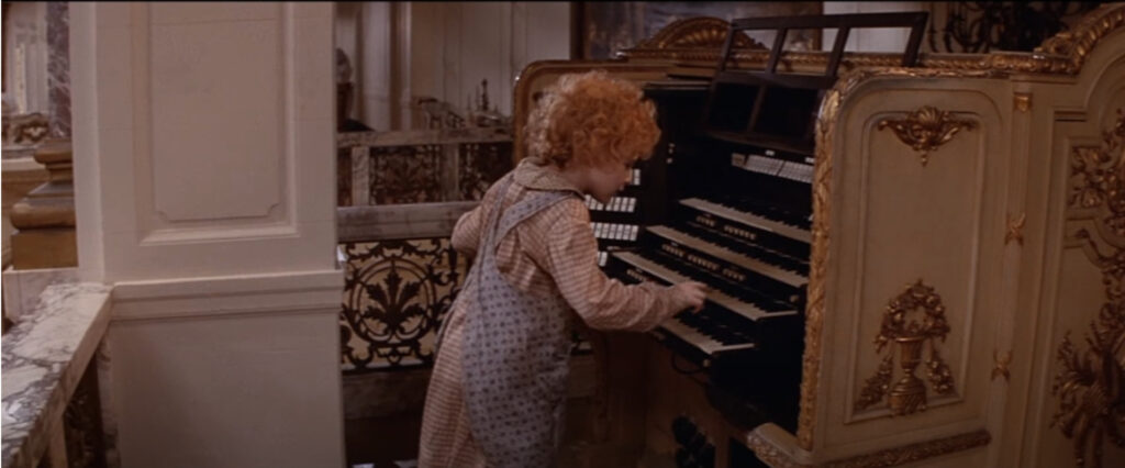 screenshot from the movie Annie: Annie playing the pipe organ in the Warbucks Mansion