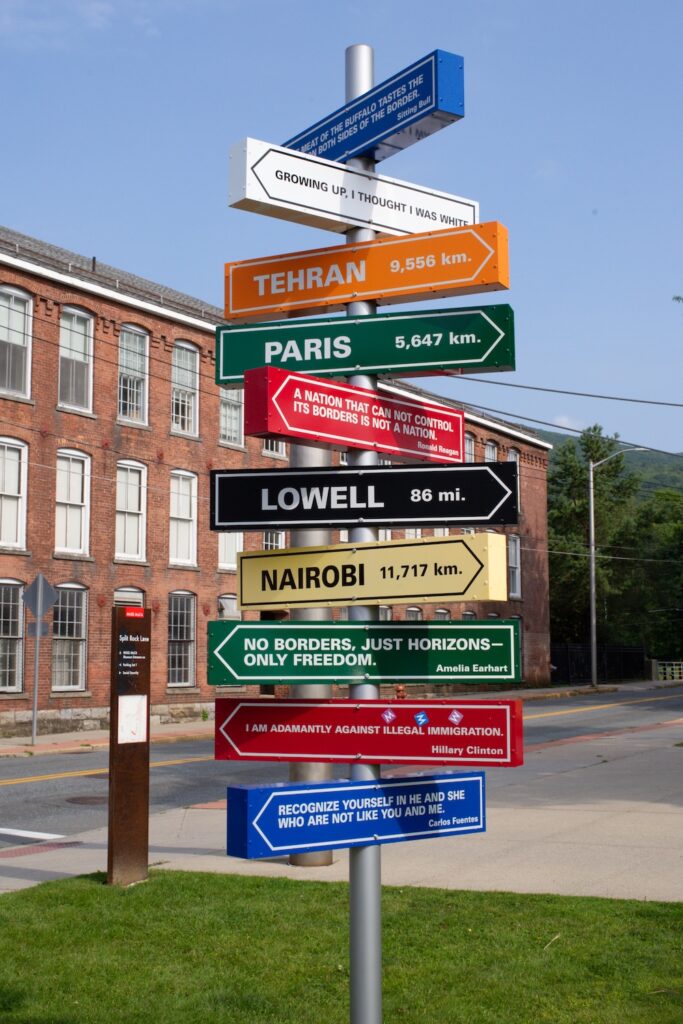 colorful mile marker posts on a pole pointing in many directions