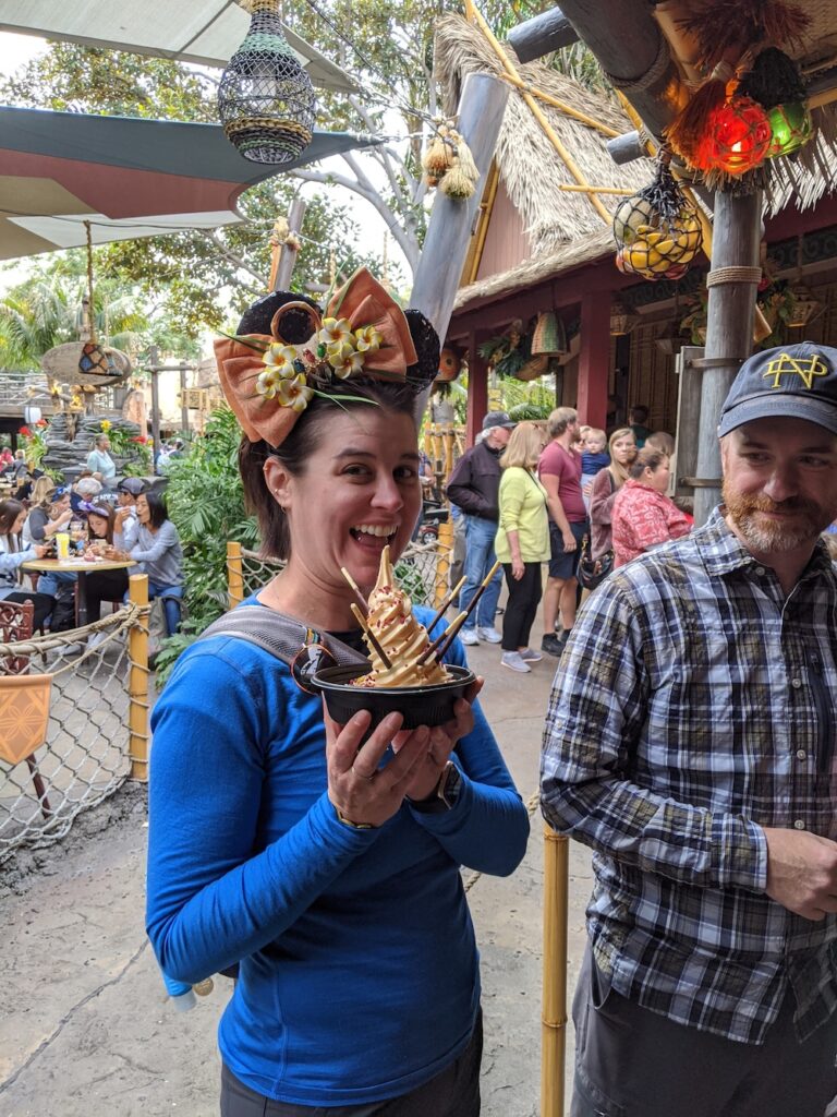 woman wearing tiki Mickey ears holding a Dole Whip at Disneyland