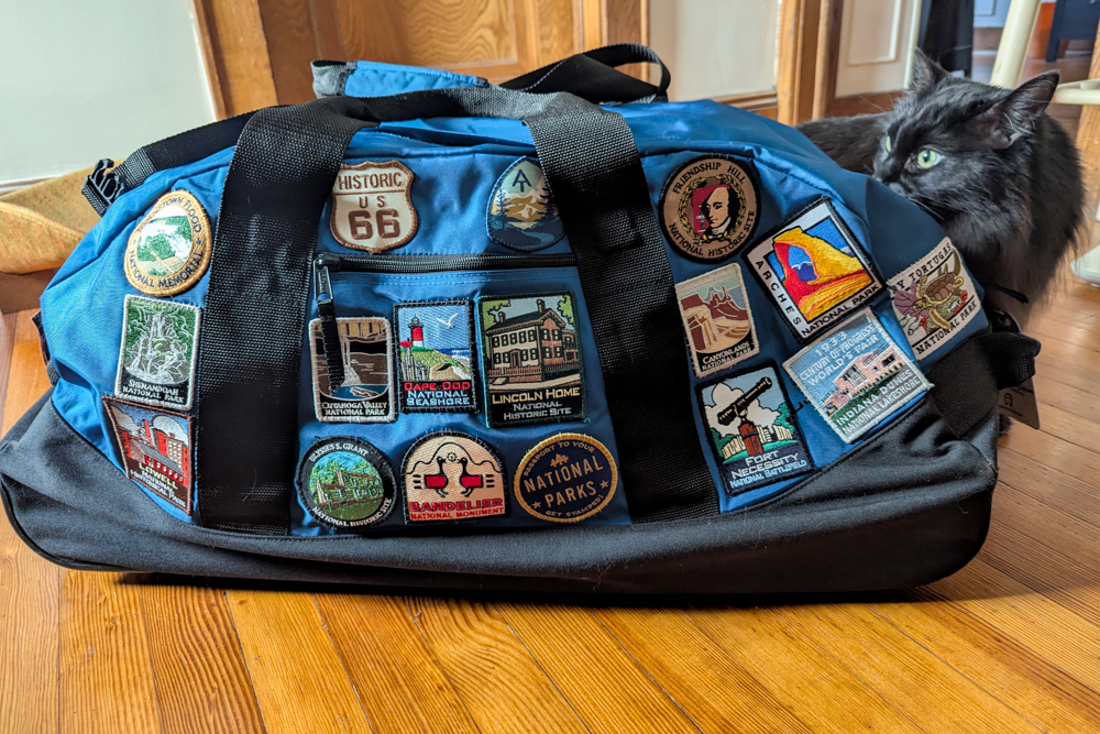 blue duffel bag covered in National Parks patches