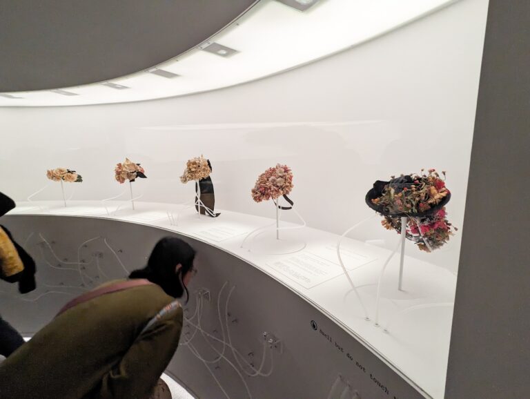 visitor at the Met Museum looking at flower hats