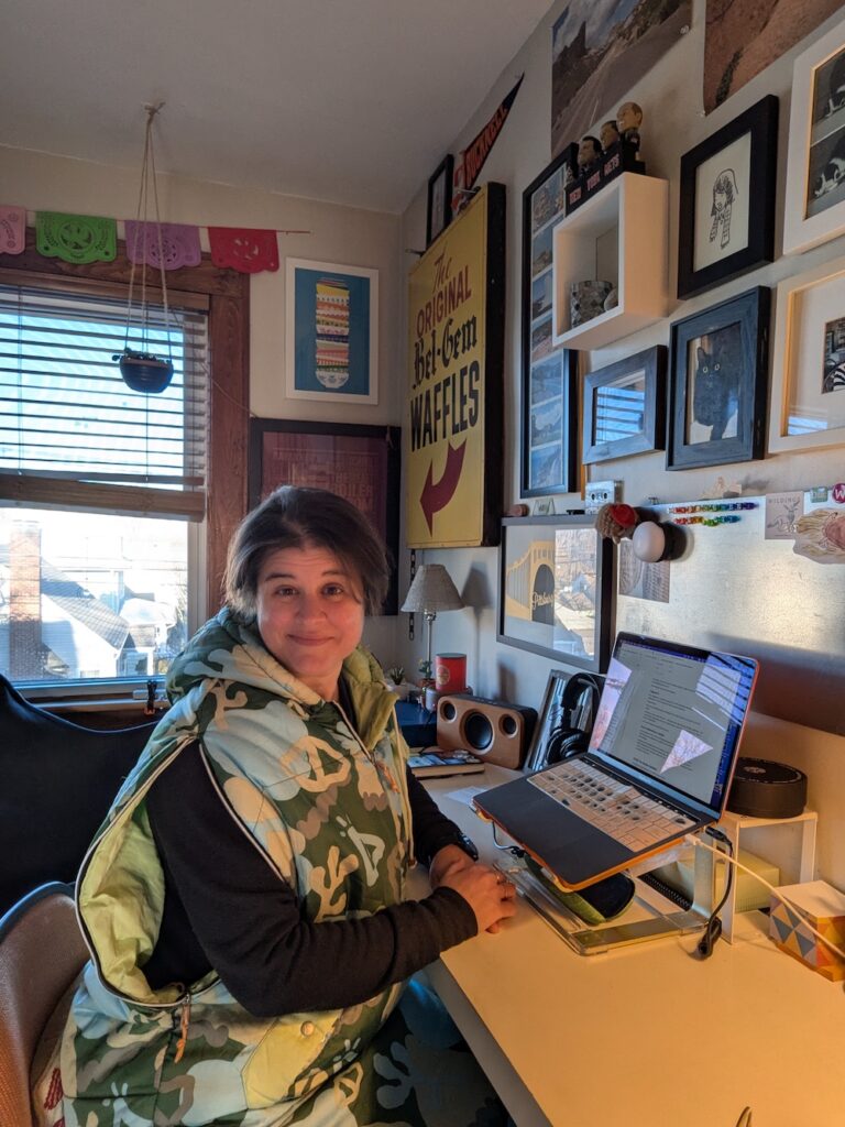 woman wearing a sleeping bag typing at a desk
