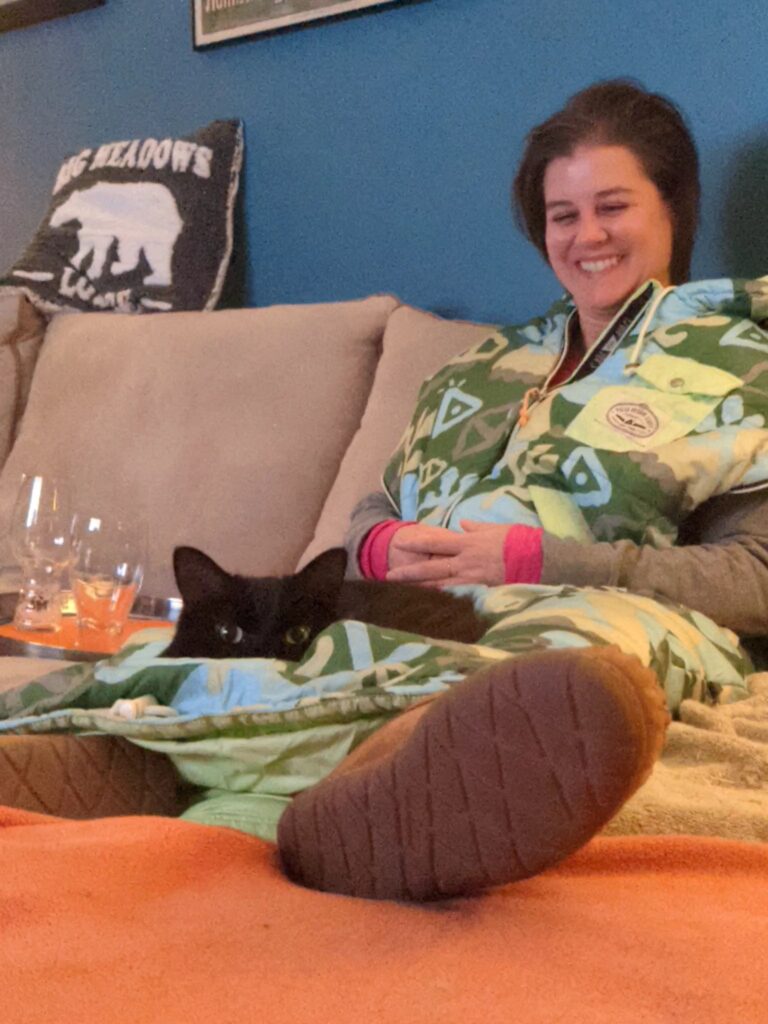 woman on couch wearing a napsack with a cat on her lap