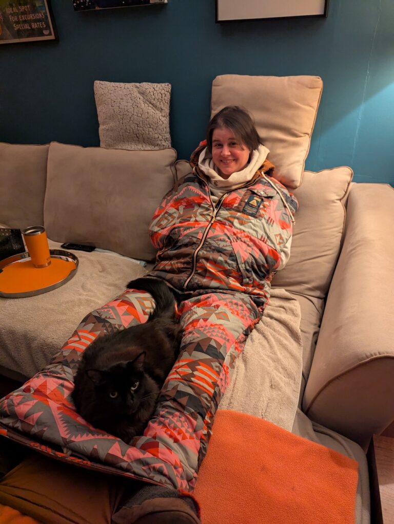 woman on couch wearing a napsack with a cat on her lap