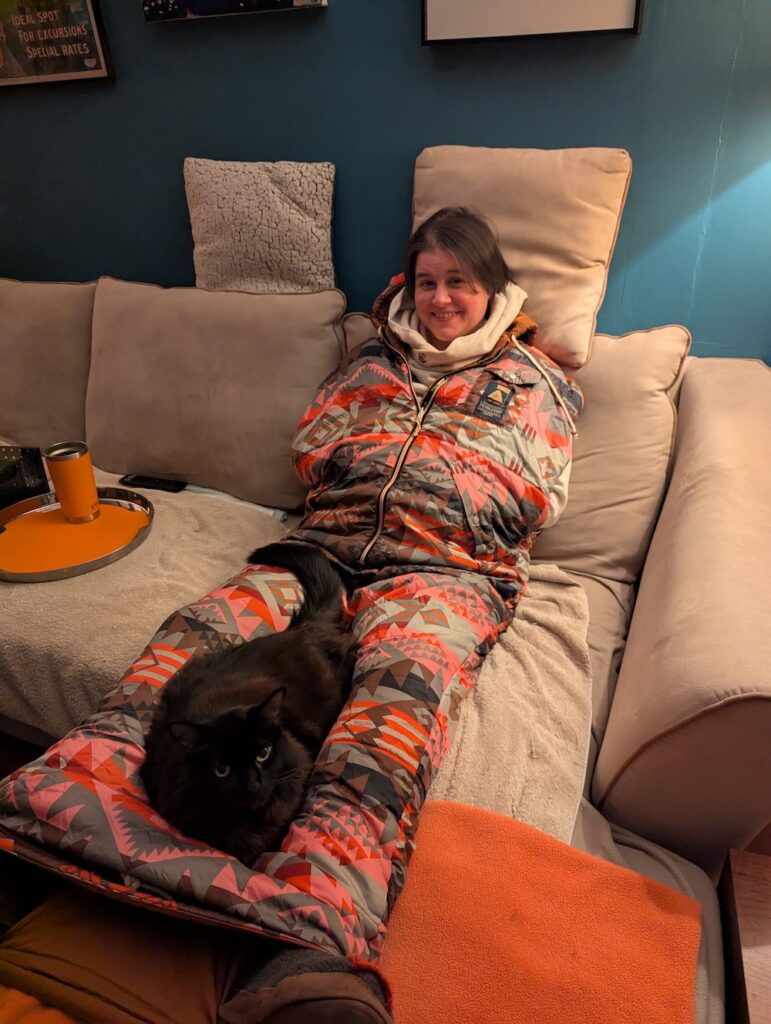 woman on couch wearing a napsack with a cat on her lap