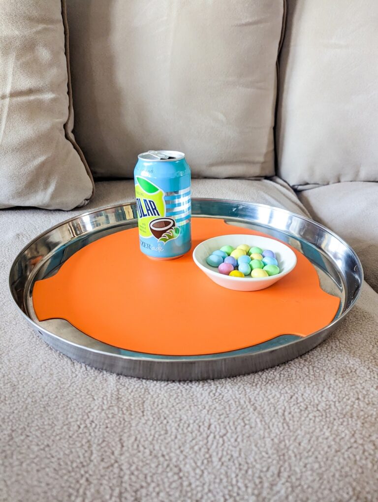 orange tray on couch with bowl of m&ms and seltzer can