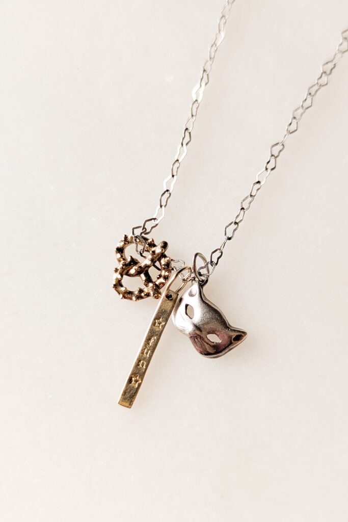 necklace charms shaped like a pretzel and a cat face mask