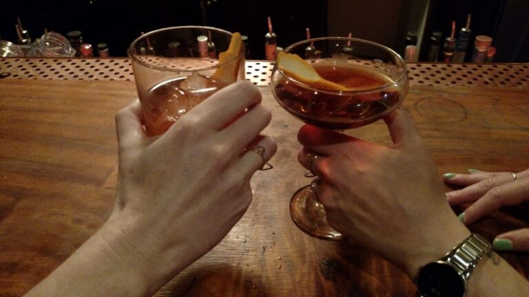two hands holding cocktails and wearing cat rings